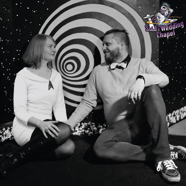 Black and white image of bride and groom sitting down smiling at each other at Sci-Fi Wedding Chapel.