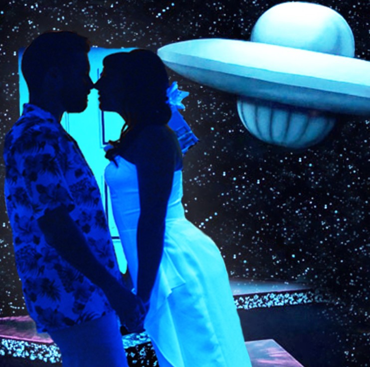 A bride and groom lit up in neon lights during their vow renewal at Sci-Fi Wedding Chapel.